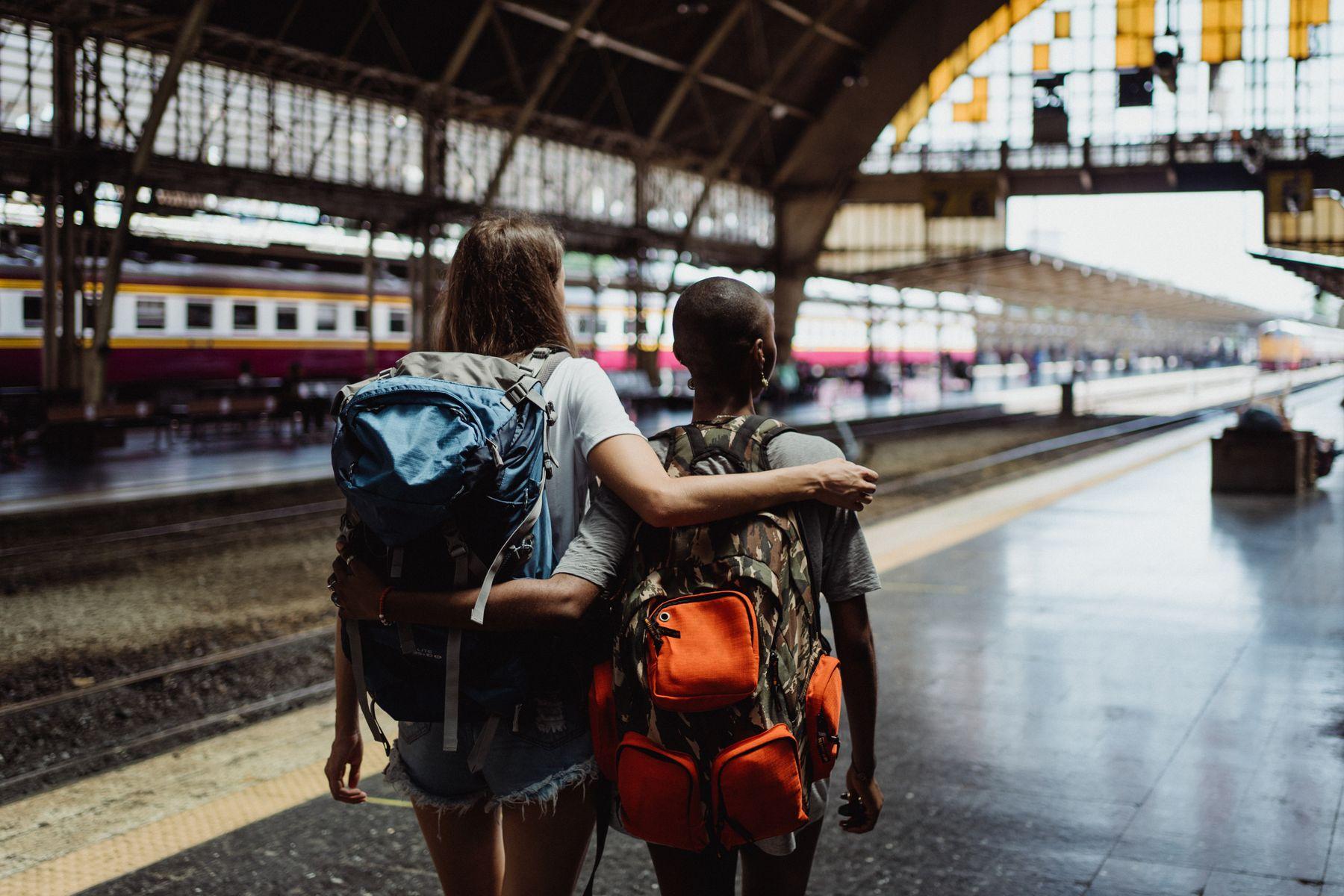 Two travelers sharing a quiet goodbye beside a sunlit train